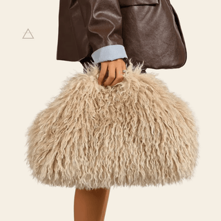 Sac Soline oversize en coloris crème, porté à la main avec une veste en cuir brun.