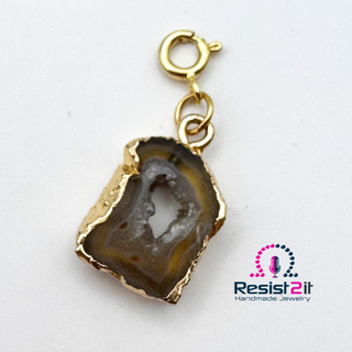 Gros plan du pendentif en agate d’Unspoken, montrant ses contours irréguliers et son centre cristallin.
